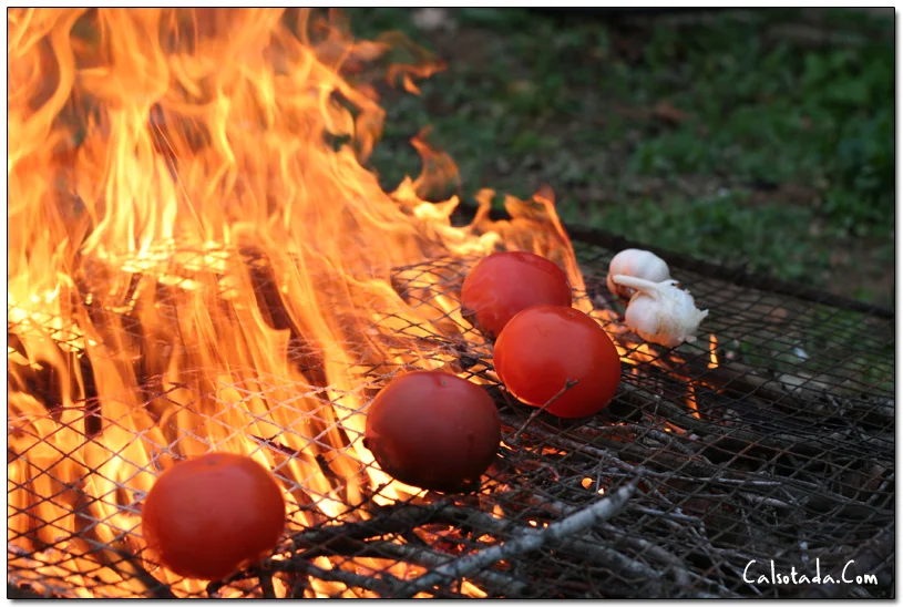 Tomàquets i alls al foc per preparar la salsa de calçots